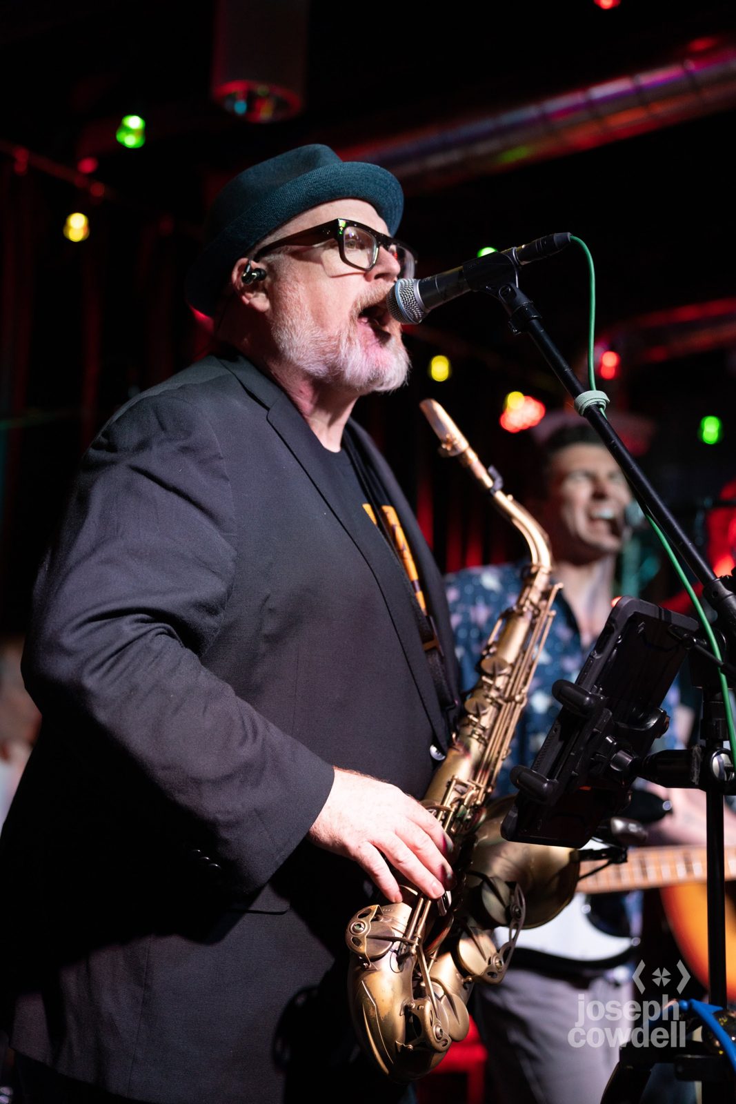 Steve Wilson singing and playing sax under stage lights