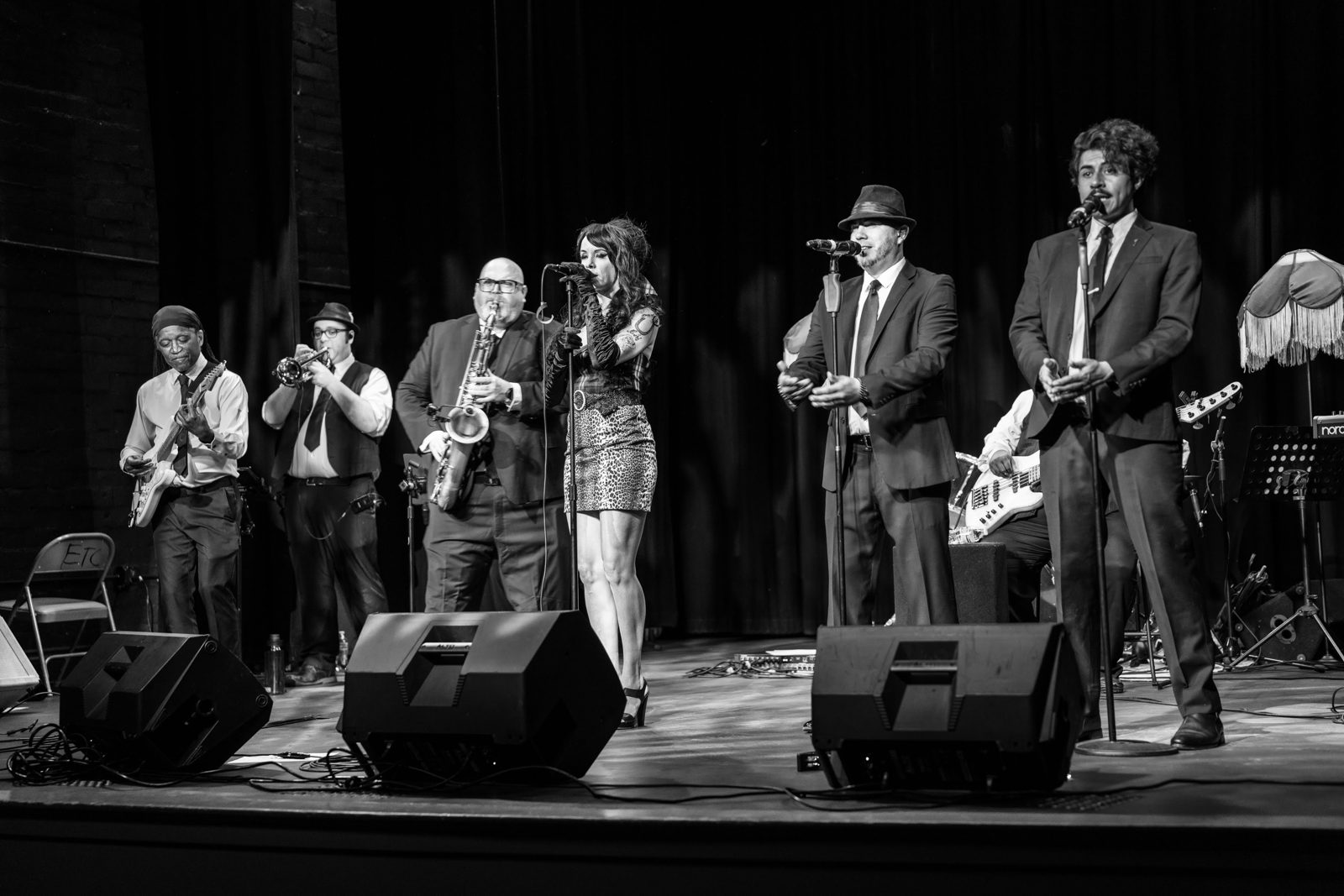 Black and white shot of the horn section on stage